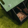 Sfeerfoto Nestera kunststof kippenhok klein, schuin vooraanzicht in een achtertuin op het gras. Het dak van het zijcompartiment is verwijderd, binnenin dit compartiment liggen 2 eieren.